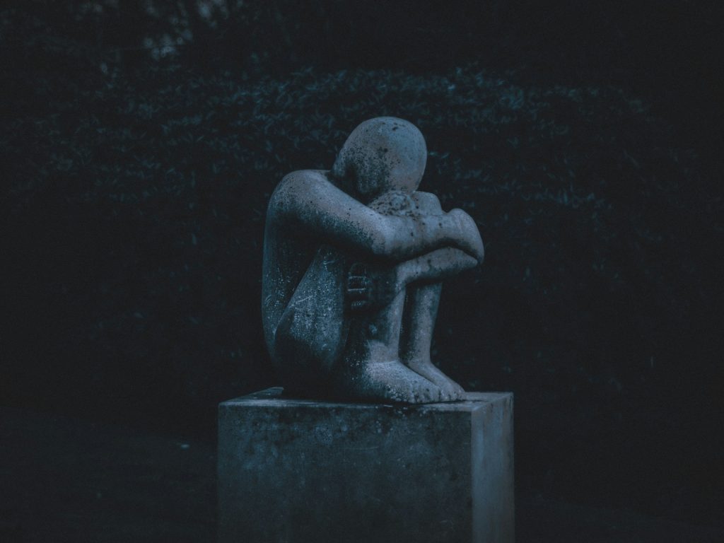 Statue of a person hugging their knees.